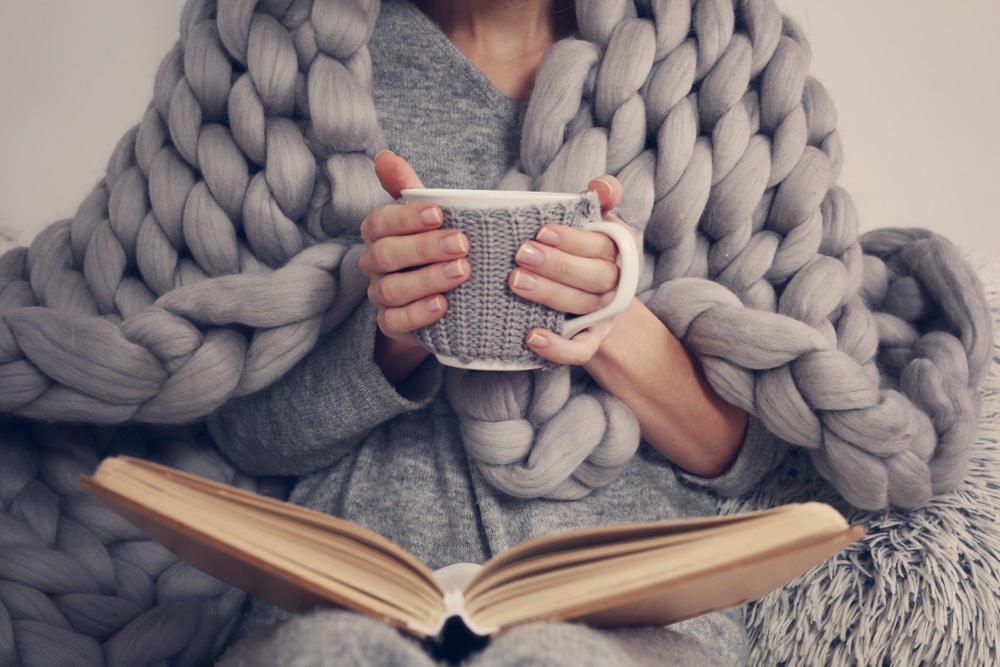 cozywomancoveredwithwarmsoftmerinowoolblanketreading